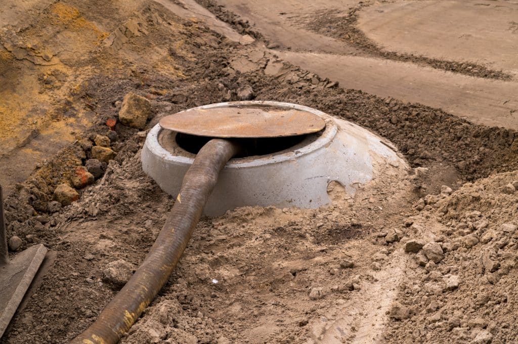 Tank Draining Services by Effluent Retrieval Septic tank pumping hose in ground during maintenance